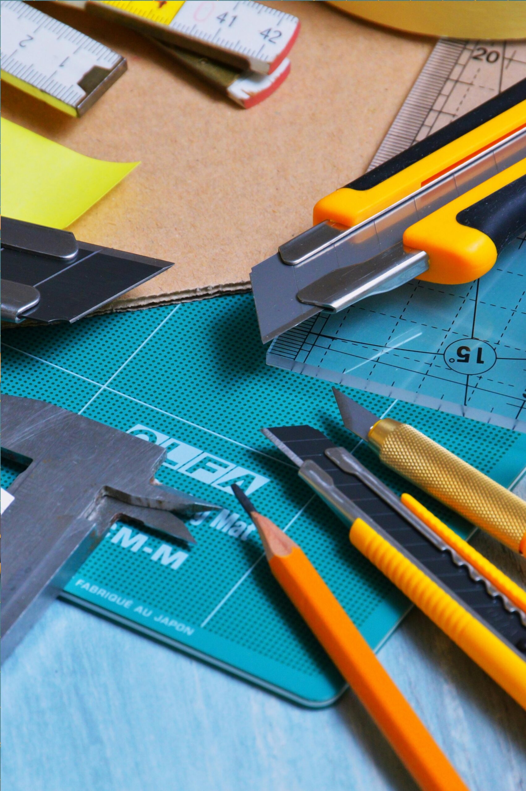 Diverse crafting tools arranged on a green cutting mat with vibrant colors.